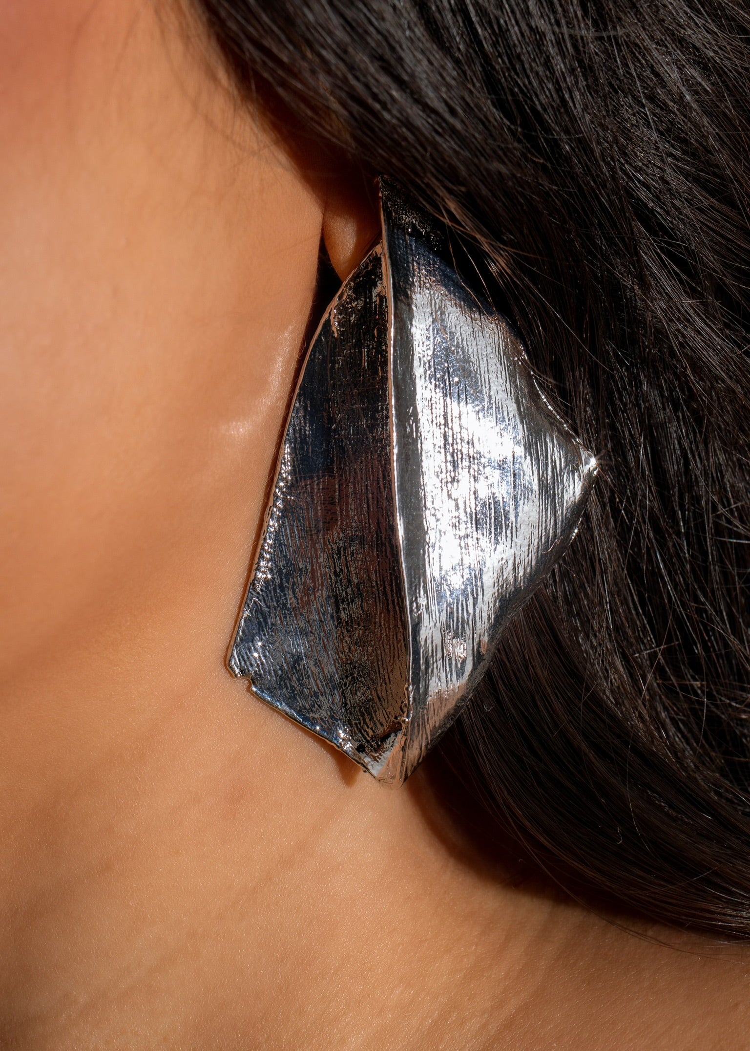 Shiny silver earring featuring a unique design, perfect for adding a touch of elegance to any outfit