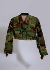 My Favorite Crop Camo Jacket Green hanging on a hanger with other clothing items in a closet