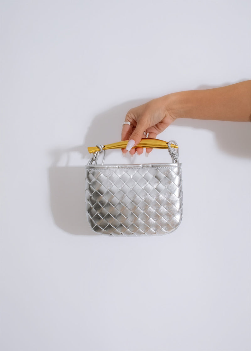 ###
A close-up of a beautiful silver handbag with intricate embroidery and shiny embellishments