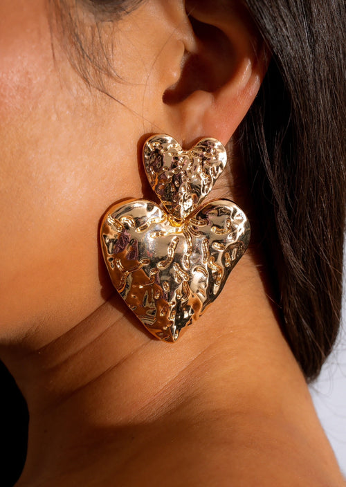 Alt text: Shiny gold heart-shaped earrings with intricate detailing and a delicate design
