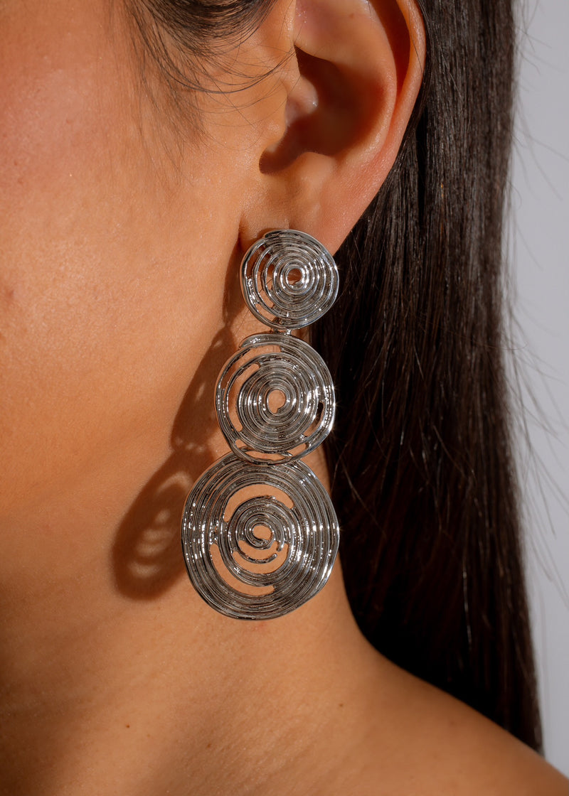 Shiny silver earrings with intricate design, perfect for a romantic date night downtown