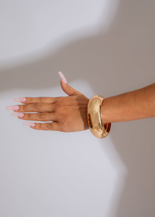 Two interlocking gold bracelets, symbolizing an unbreakable bond, shining in the light