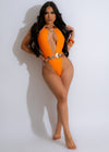 Beautiful woman wearing a vibrant orange Summer Love Swimsuit, enjoying the sunshine on a sandy beach 