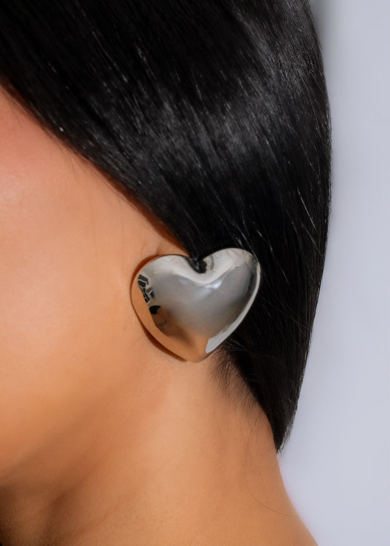 Shiny silver heart-shaped earrings with intricate design and dramatic flair