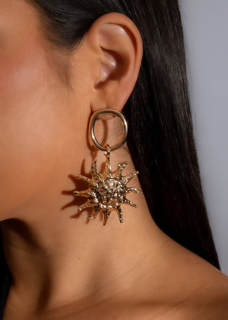 A pair of gold sunshine shaped earrings, featuring a radiant design