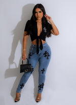 Alt text: Dark blue denim jeans with a leather cross design on the back pocket