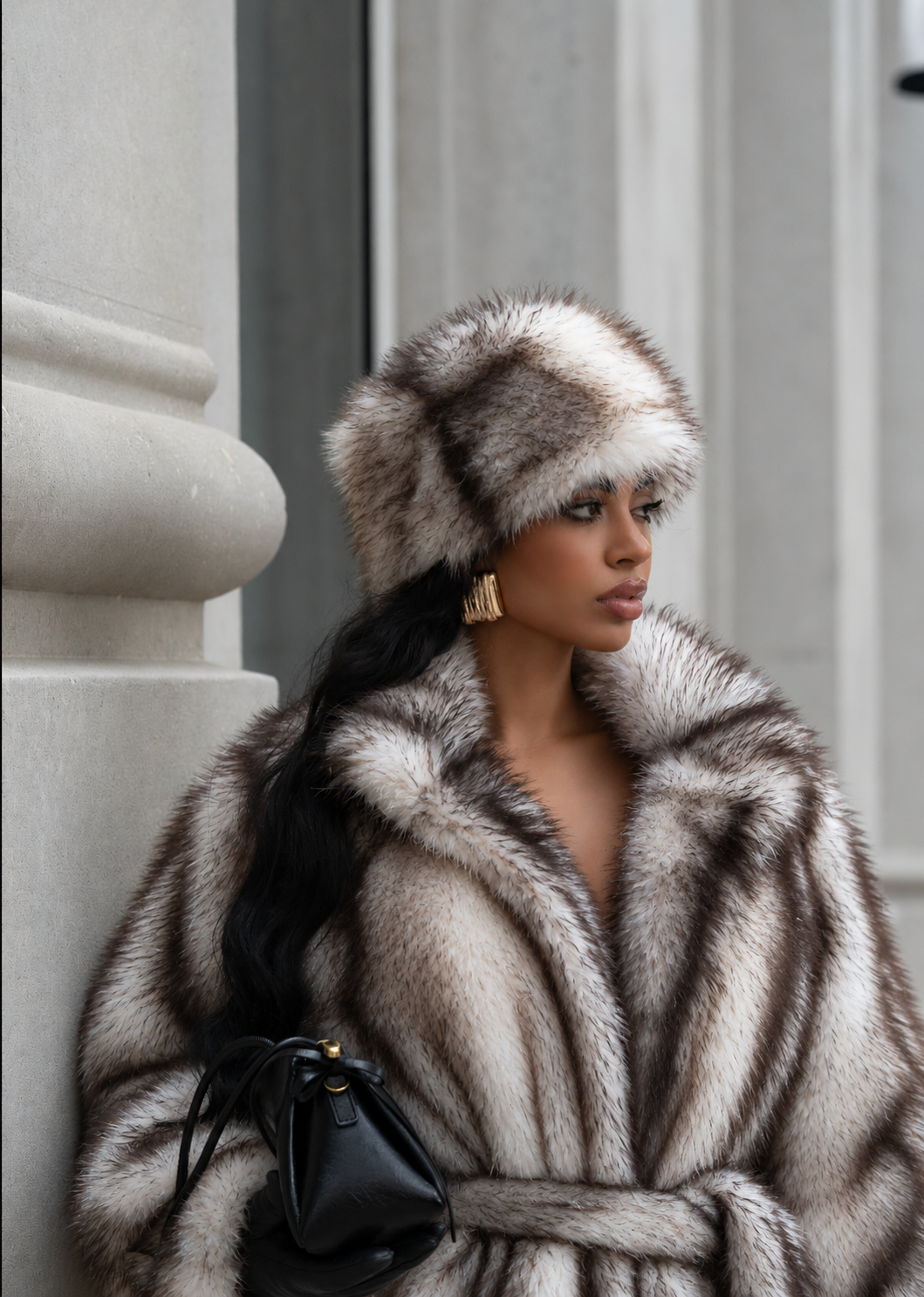 Model wearing a plush white and gray faux fur winter hat