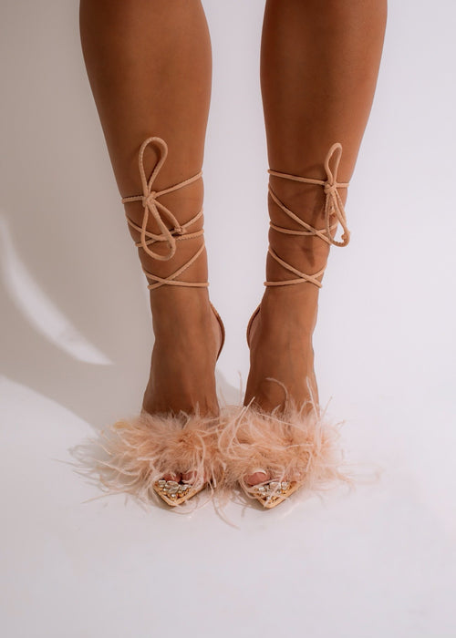 Close-up of nude-colored high heels with pointed toe and thin ankle strap